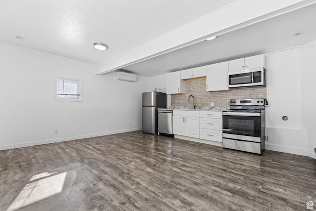 789 27th St, Ogden, UT 84403 - kitchen with dark wood-type flooring, appliances with stainless steel finishes, a wall mounted air conditioner, white cabinets, and decorative backsplash