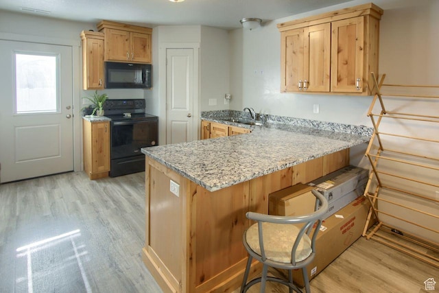 2460 W 450 N # 10, Tremonton, UT 84337 - kitchen featuring a breakfast bar area, light stone counters, kitchen peninsula, light hardwood / wood-style floors, and black appliances