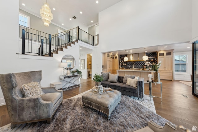 2905 E Denmark Dr, Cottonwood Heights, UT 84121 - living room with a notable chandelier, a healthy amount of sunlight, stairs, a towering ceiling, and wood finished floors