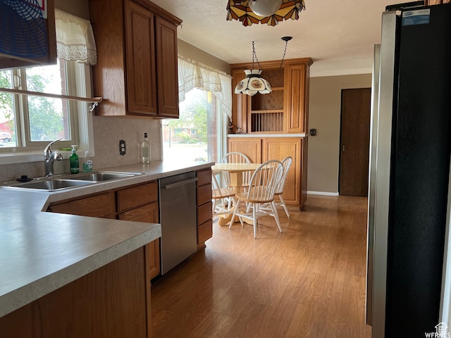 kitchen featuring sink, decorative light fixtures, stainless steel appliances, light hardwood / wood-style floors, and backsplash
