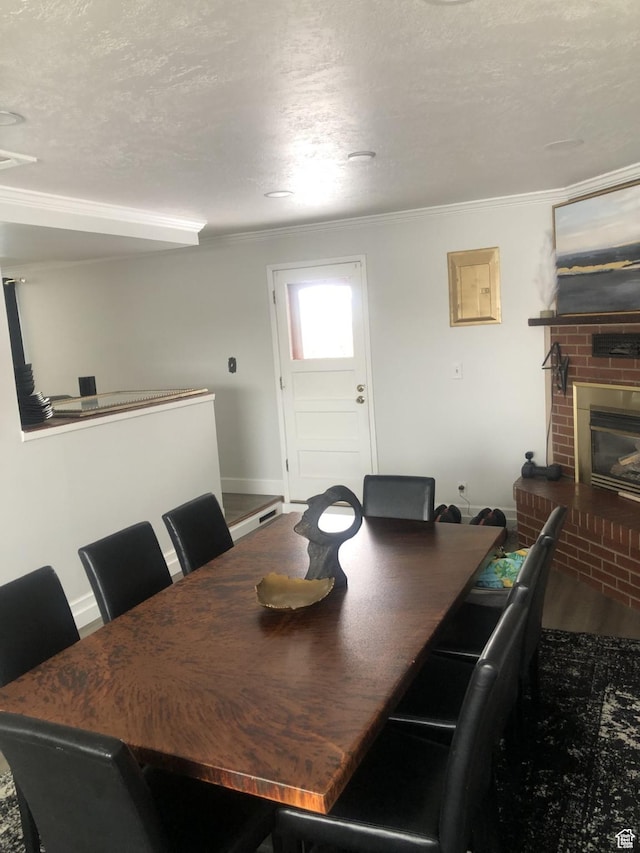 dining area with ornamental molding, a textured ceiling, and a fireplace