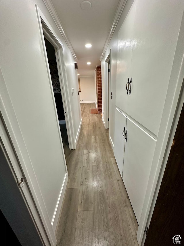 hallway featuring ornamental molding and light hardwood / wood-style floors