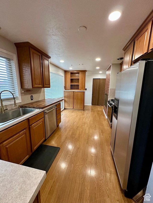 kitchen featuring stainless steel appliances, light hardwood / wood-style floors, sink, and a textured ceiling