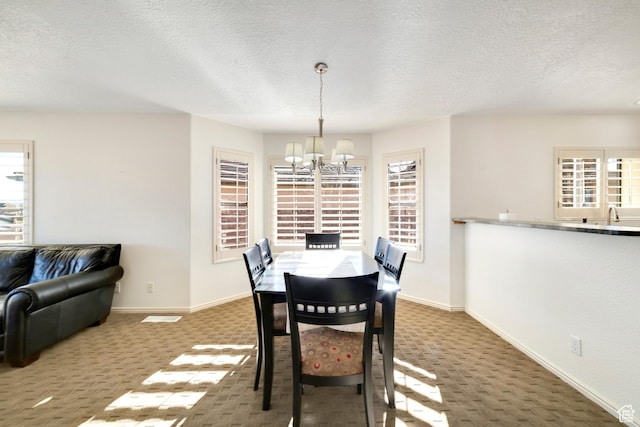 dining area featuring a chandelier, carpet, baseboards, and a textured ceiling
