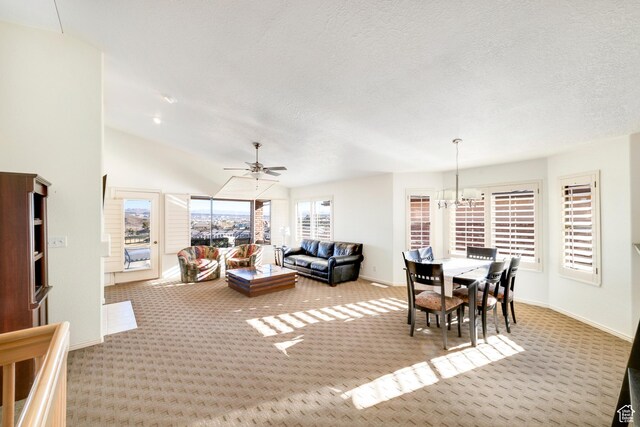 carpeted living room featuring baseboards, a ceiling fan, a chandelier, lofted ceiling, and a textured ceiling