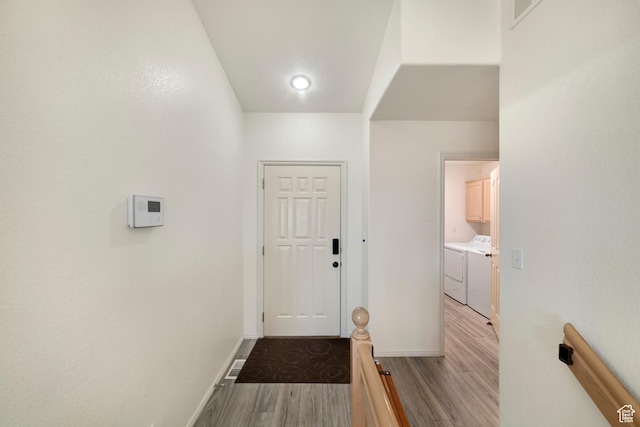 doorway with light wood-style floors, independent washer and dryer, and baseboards