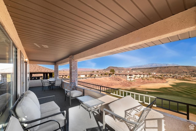 view of patio featuring a mountain view, outdoor dining area, view of golf course, and a balcony