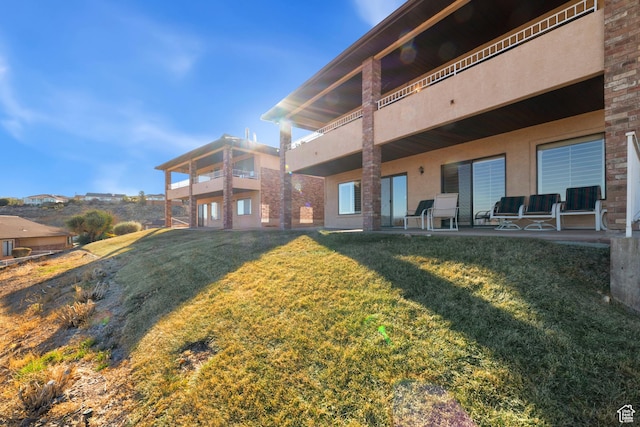 view of green lawn featuring a balcony and a patio area