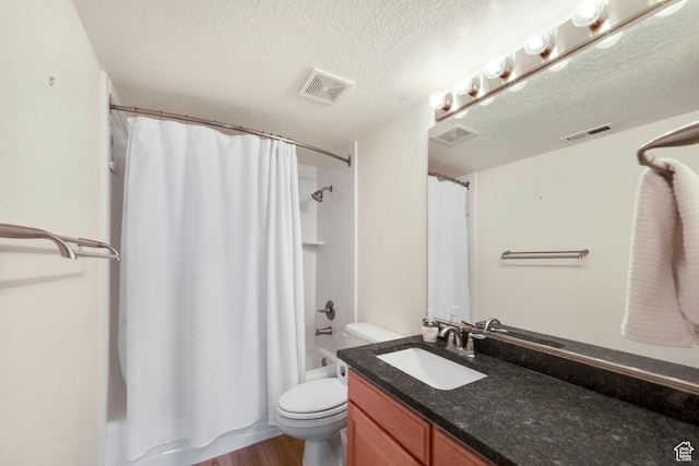 bathroom featuring toilet, vanity, a textured ceiling, shower / tub combo with curtain, and wood finished floors