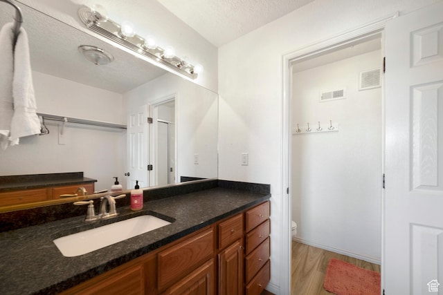 full bath featuring wood finished floors, toilet, a textured ceiling, and vanity