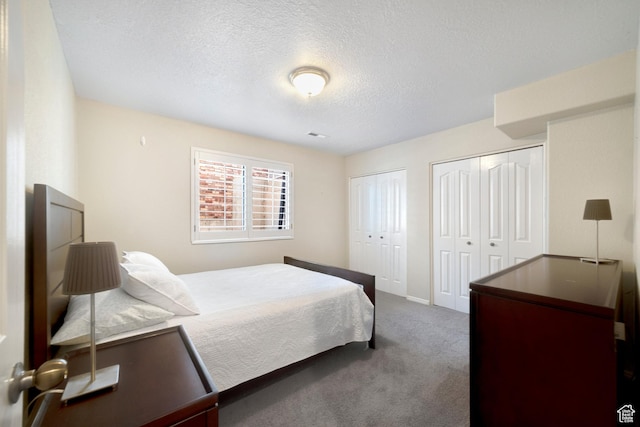carpeted bedroom with multiple closets, a textured ceiling, and baseboards