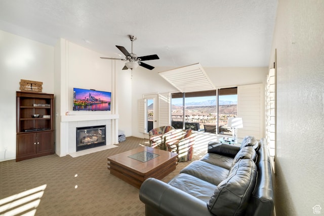 living area with vaulted ceiling, a fireplace, carpet flooring, and a ceiling fan