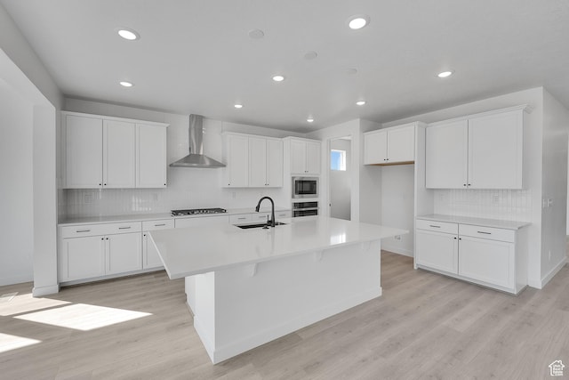 1162 N 375th St W Unit 22, Harrisville, UT 84404 - kitchen with a center island with sink, a sink, stainless steel appliances, wall chimney exhaust hood, and light wood finished floors