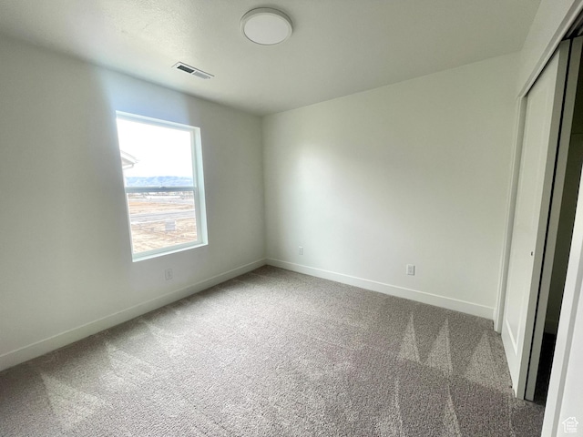 unfurnished bedroom with visible vents, carpet flooring, baseboards, and a closet