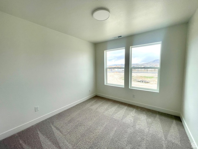 empty room with carpet flooring, baseboards, and visible vents