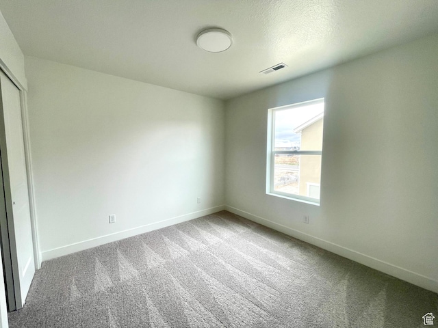 unfurnished bedroom featuring carpet floors, baseboards, visible vents, and a closet
