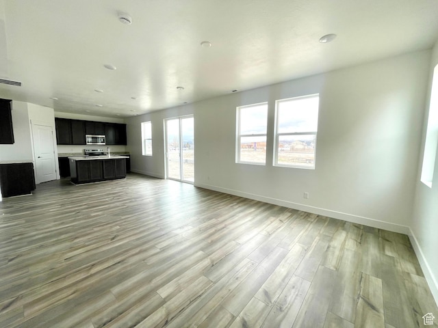 unfurnished living room featuring baseboards, a sink, and light wood-type flooring