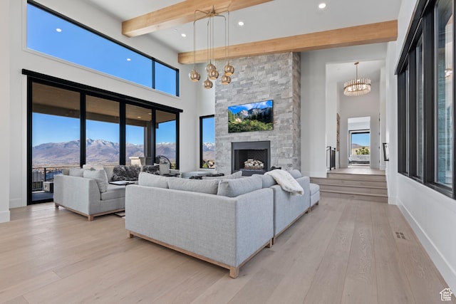 2066 E Oquirrh Mountain Cir, Heber City, UT 84032 - living area featuring beamed ceiling, light wood-style floors, a fireplace, a healthy amount of sunlight, and a chandelier