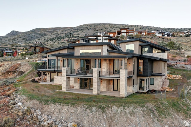2066 E Oquirrh Mountain Cir, Heber City, UT 84032 - rear view of house featuring stone siding, a mountain view, a patio, and a balcony