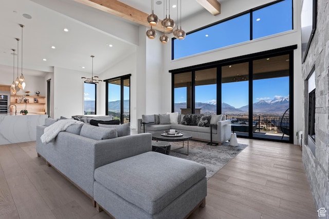 2066 E Oquirrh Mountain Cir, Heber City, UT 84032 - living room featuring wood finished floors, beam ceiling, a high ceiling, a mountain view, and a chandelier