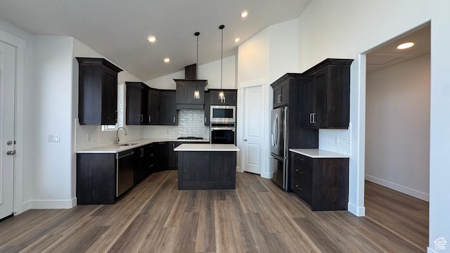 kitchen with appliances with stainless steel finishes, a sink, light countertops, a kitchen island, and vaulted ceiling