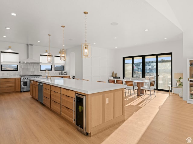 9749 N Hibiscus Ln, Eagle Mountain, UT 84005 - kitchen with wall chimney exhaust hood, beverage cooler, appliances with stainless steel finishes, light wood-type flooring, and recessed lighting