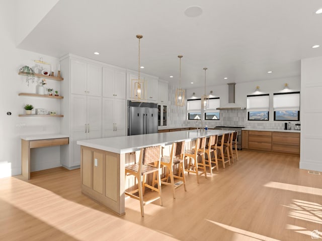 9749 N Hibiscus Ln, Eagle Mountain, UT 84005 - kitchen with high quality appliances, wall chimney exhaust hood, light wood-style flooring, a large island with sink, and recessed lighting