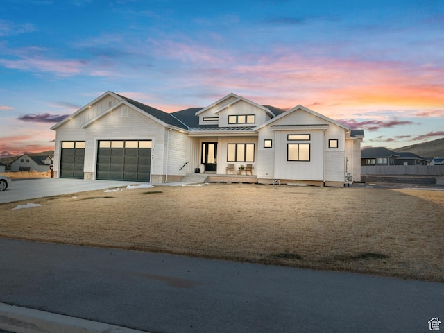 9749 N Hibiscus Ln, Eagle Mountain, UT 84005 - modern inspired farmhouse featuring a standing seam roof, an attached garage, metal roof, concrete driveway, and covered porch