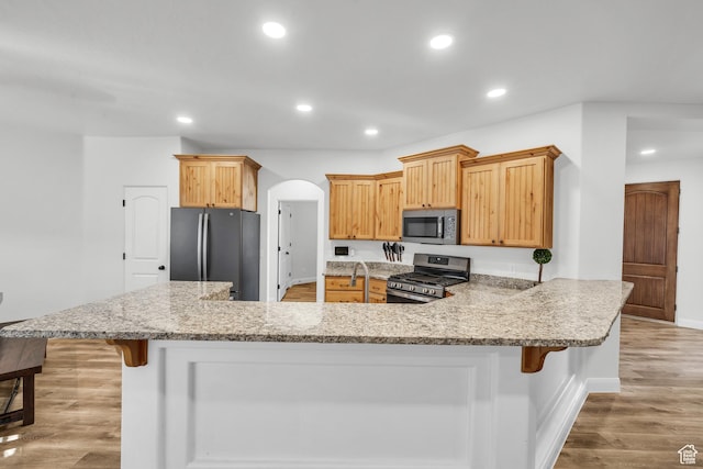 235 W Golden Eagle Cir, St George, UT 84770 - kitchen featuring light stone counters, stainless steel appliances, a breakfast bar, and light hardwood / wood-style flooring