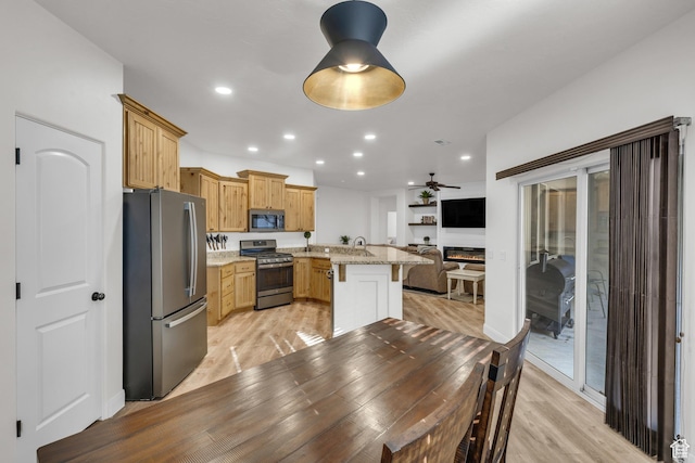 235 W Golden Eagle Cir, St George, UT 84770 - kitchen featuring appliances with stainless steel finishes, sink, a kitchen breakfast bar, light stone counters, and light hardwood / wood-style floors