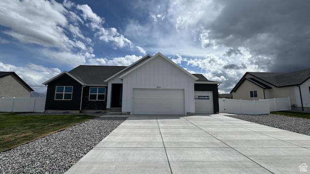 view of front of property with board and batten siding, an attached garage, concrete driveway, and fence