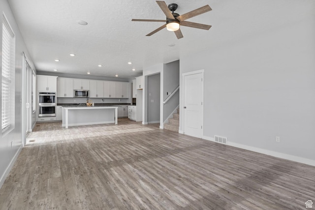 4421 W 150 N, West Point, UT 84015 - unfurnished living room with ceiling fan, plenty of natural light, light hardwood / wood-style flooring, and a textured ceiling