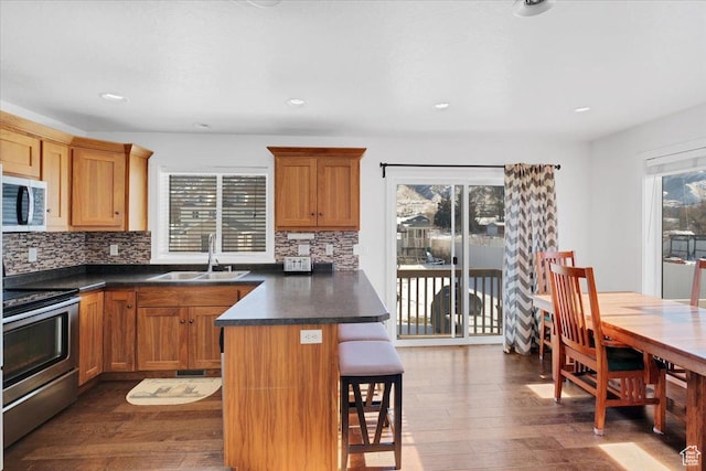 820 S 525 E, River Heights, UT 84321 - kitchen with dark countertops, a sink, a kitchen breakfast bar, dark wood finished floors, and stainless steel appliances