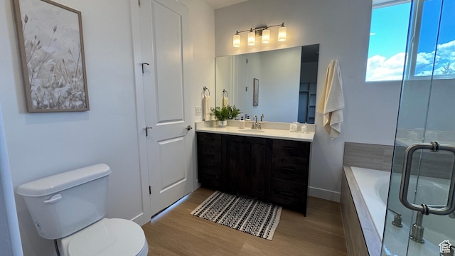 full bathroom featuring wood finished floors, toilet, tiled bath, and vanity