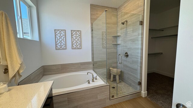 bathroom with a stall shower, a garden tub, a walk in closet, and vanity