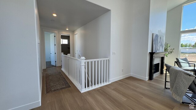 hall with an upstairs landing, wood finished floors, recessed lighting, and baseboards