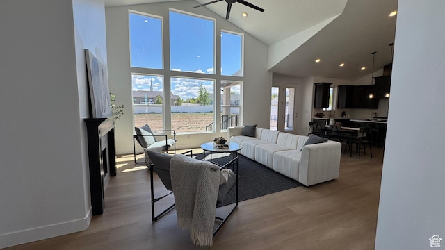 living area featuring high vaulted ceiling, a ceiling fan, wood finished floors, recessed lighting, and a water view