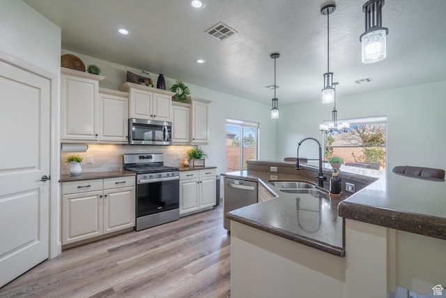 205 E Gold Bullion Way, Washington, UT 84780 - kitchen with sink, hanging light fixtures, appliances with stainless steel finishes, white cabinets, and backsplash