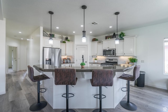 205 E Gold Bullion Way, Washington, UT 84780 - kitchen featuring white cabinetry, a breakfast bar area, hanging light fixtures, a large island, and stainless steel appliances