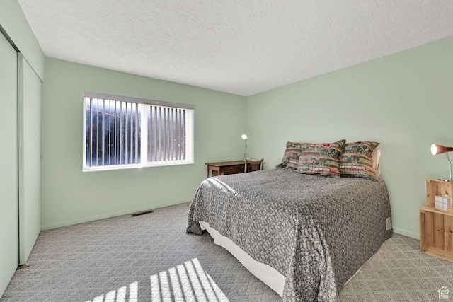 bedroom with carpet floors, a textured ceiling, baseboards, and a closet