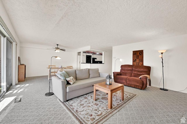 carpeted living area featuring a ceiling fan and a textured ceiling