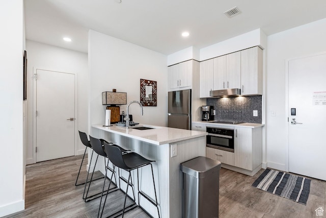 2303 Deer Hollow Rd Unit 1329, Park City, UT 84060 - kitchen with appliances with stainless steel finishes, sink, a breakfast bar area, decorative backsplash, and light hardwood / wood-style floors