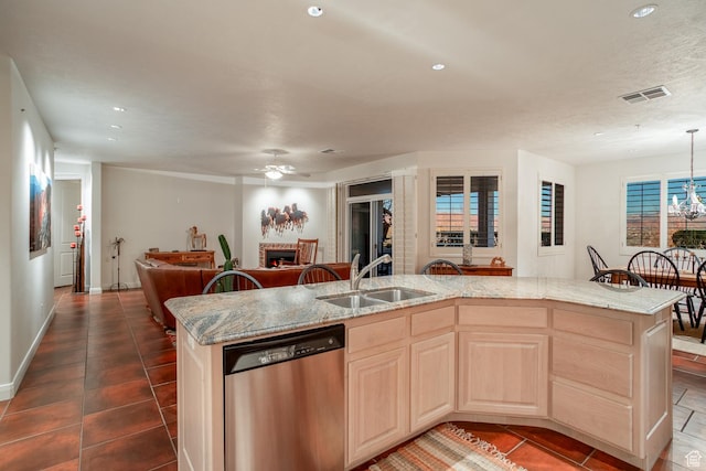 kitchen featuring light brown cabinetry, sink, stainless steel dishwasher, and a center island with sink