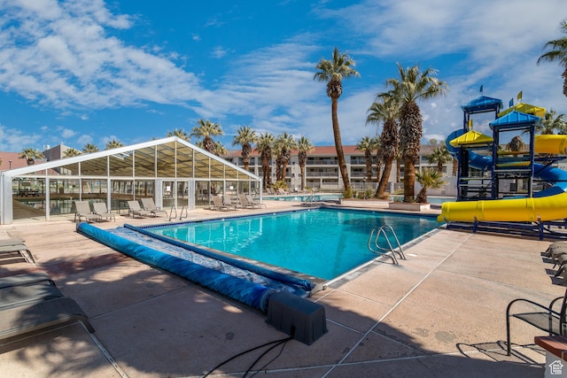 view of swimming pool with a water slide and a patio area