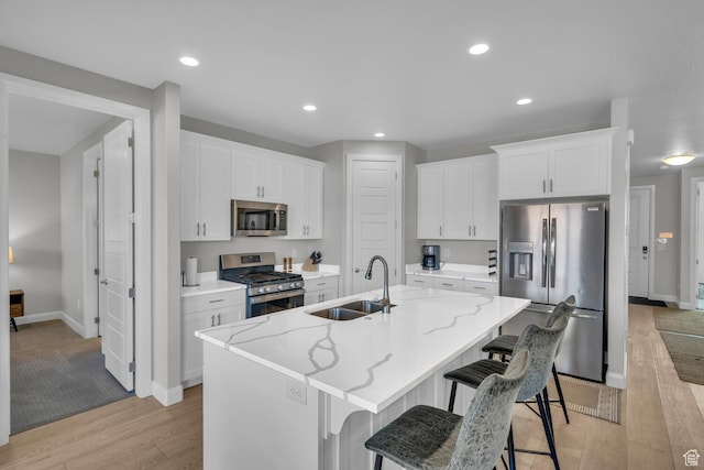 1439 N Arena Roja Dr, Washington, UT 84780 - kitchen with an island with sink, white cabinetry, sink, light stone counters, and stainless steel appliances