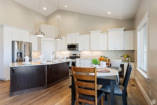 1407 N Mountain Rd, Ogden, UT 84404 - kitchen featuring a kitchen island with sink, hanging light fixtures, white cabinetry, and stainless steel appliances