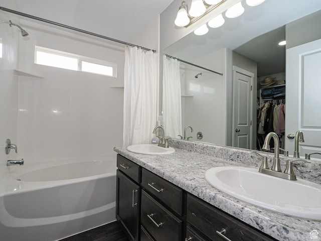 full bathroom featuring double vanity, a spacious closet, shower / bath combo, and a sink