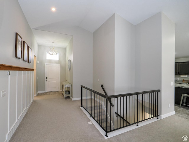 hall featuring light carpet, an upstairs landing, a chandelier, and vaulted ceiling