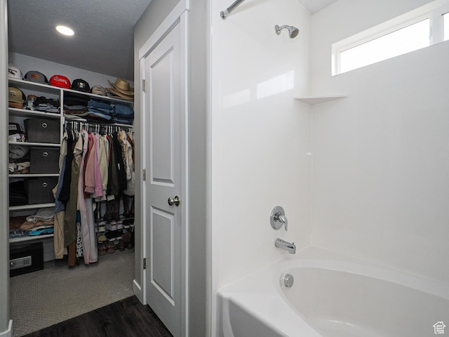 bathroom featuring shower / tub combination, wood finished floors, a spacious closet, and a textured ceiling