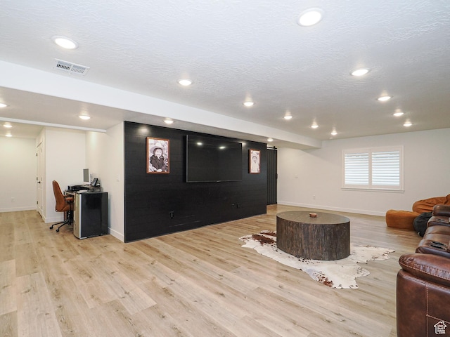 living area with recessed lighting, visible vents, light wood-style flooring, and a textured ceiling